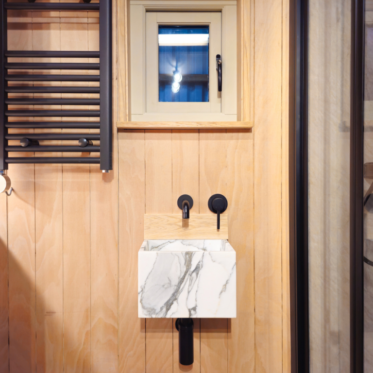 WildNomadShepherdsHutForSaleBathroomwithHeatedTowelRail MarbleSink ShowerandMattBlackTaps 768x768